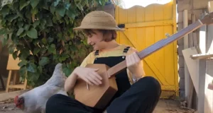 Phoebe’s music video, fretless banjo, charming chicken, Down in the River to Pray, authenticity, whimsical, homely vibe, heartfelt performance, simplicity, nostalgia.