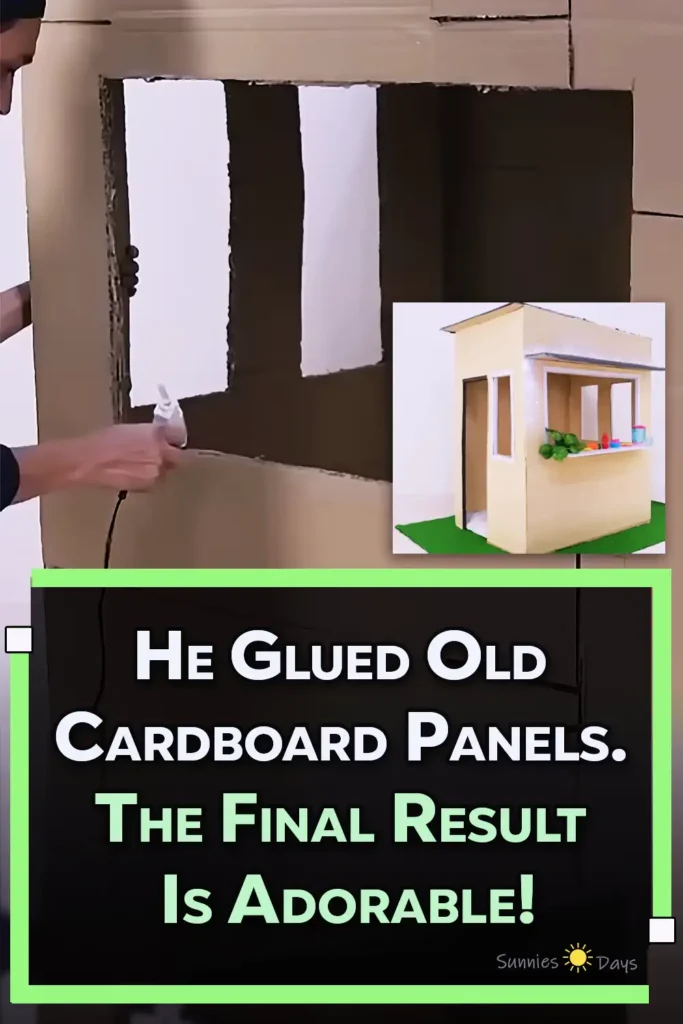 A finished child-sized playhouse made from large cardboard panels, featuring a wide serving window, cardboard counter, side doorway, narrow windows, dark roof awning, string lights, toy food, and a green floor mat.